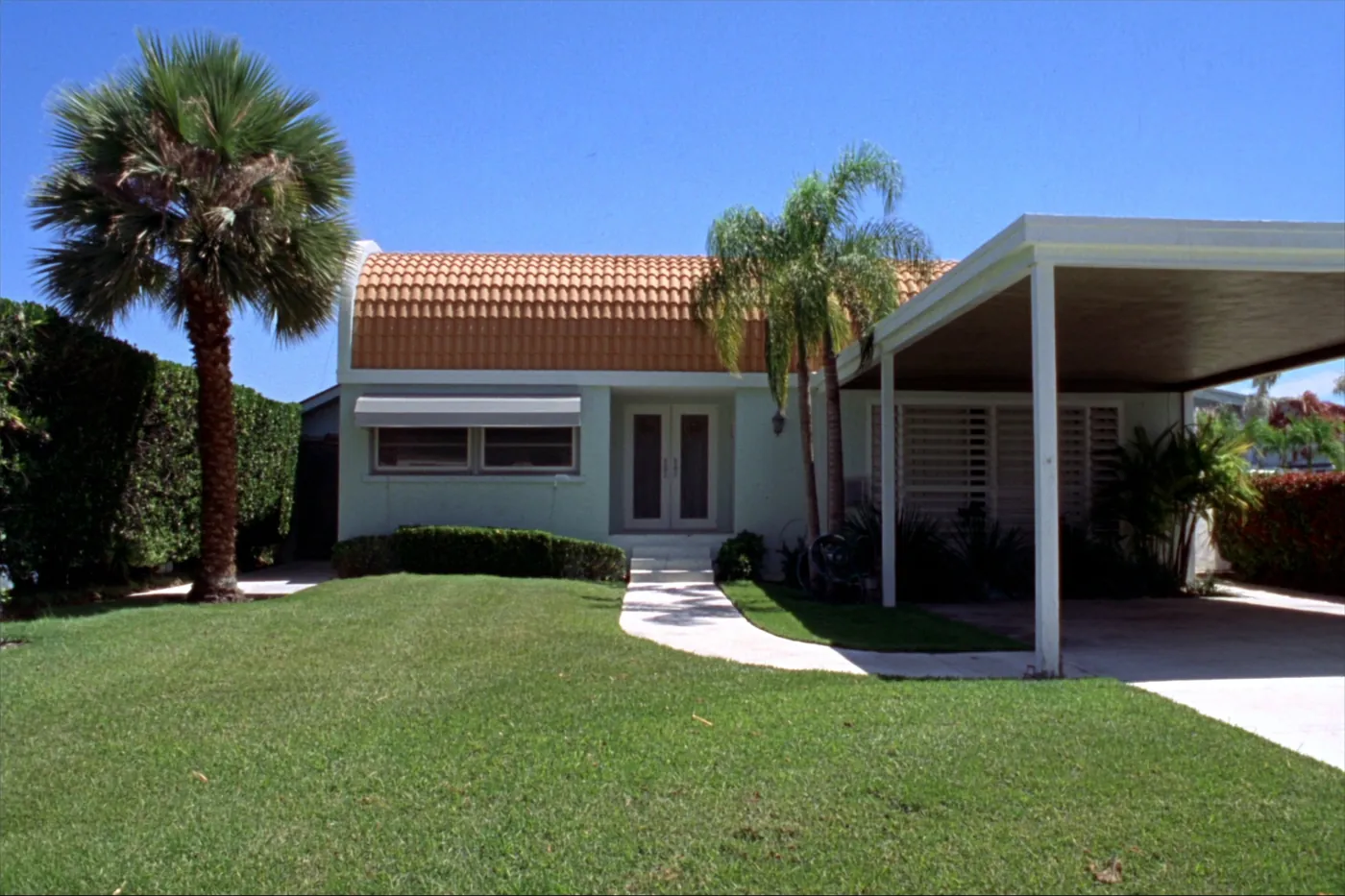An empty older South Florida house seen from the front lawn