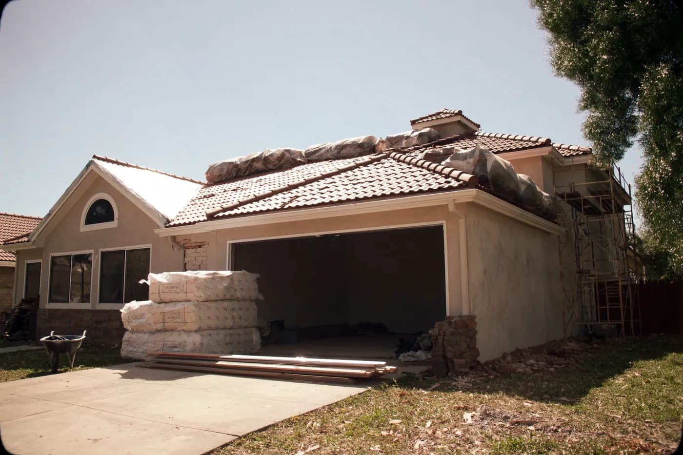 A South Florida house mid-renovation with a partially replaced tile roof and materials on site